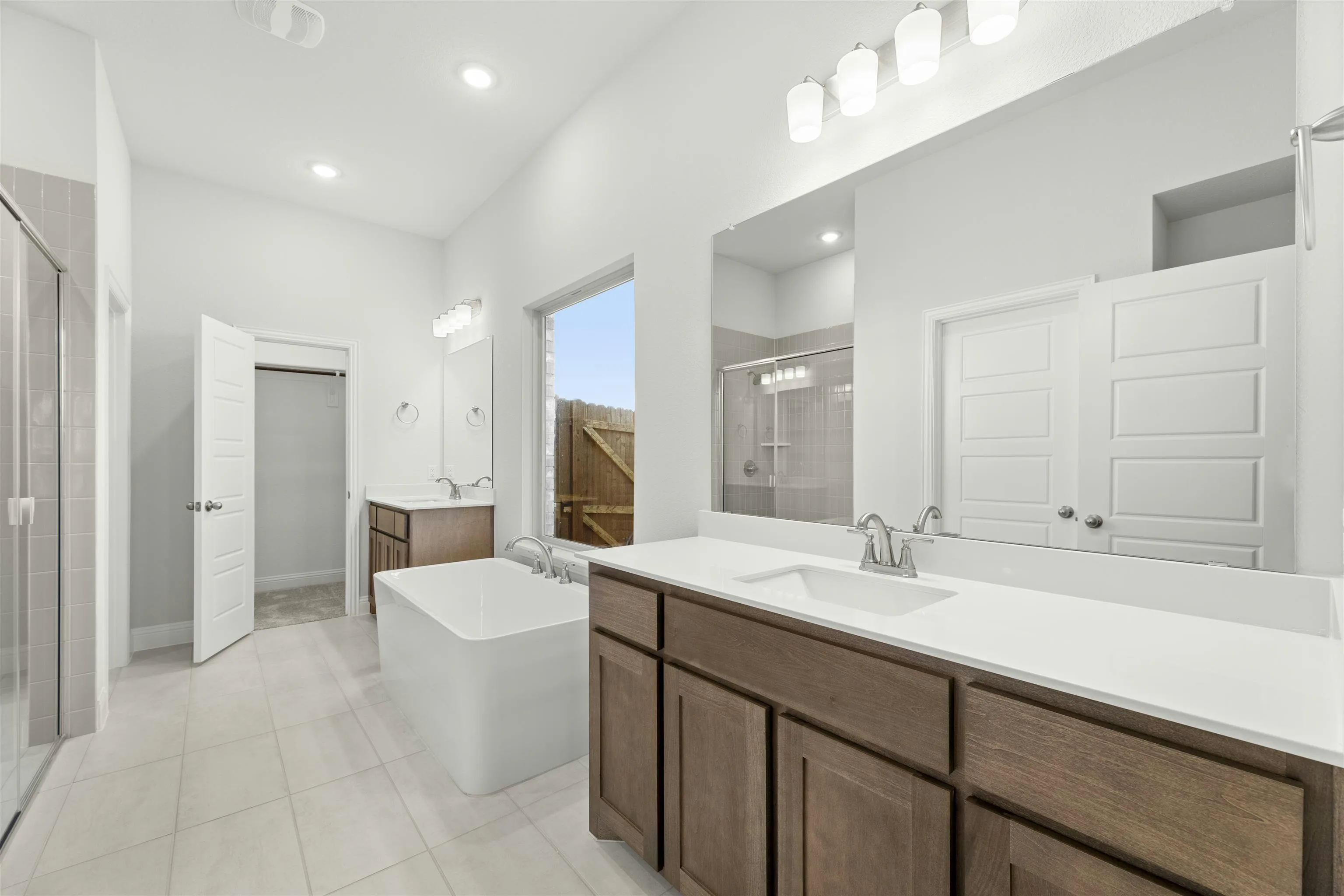 Primary bathroom with dual vanities and freestanding tub in a new traditional style home by Kindred Homes