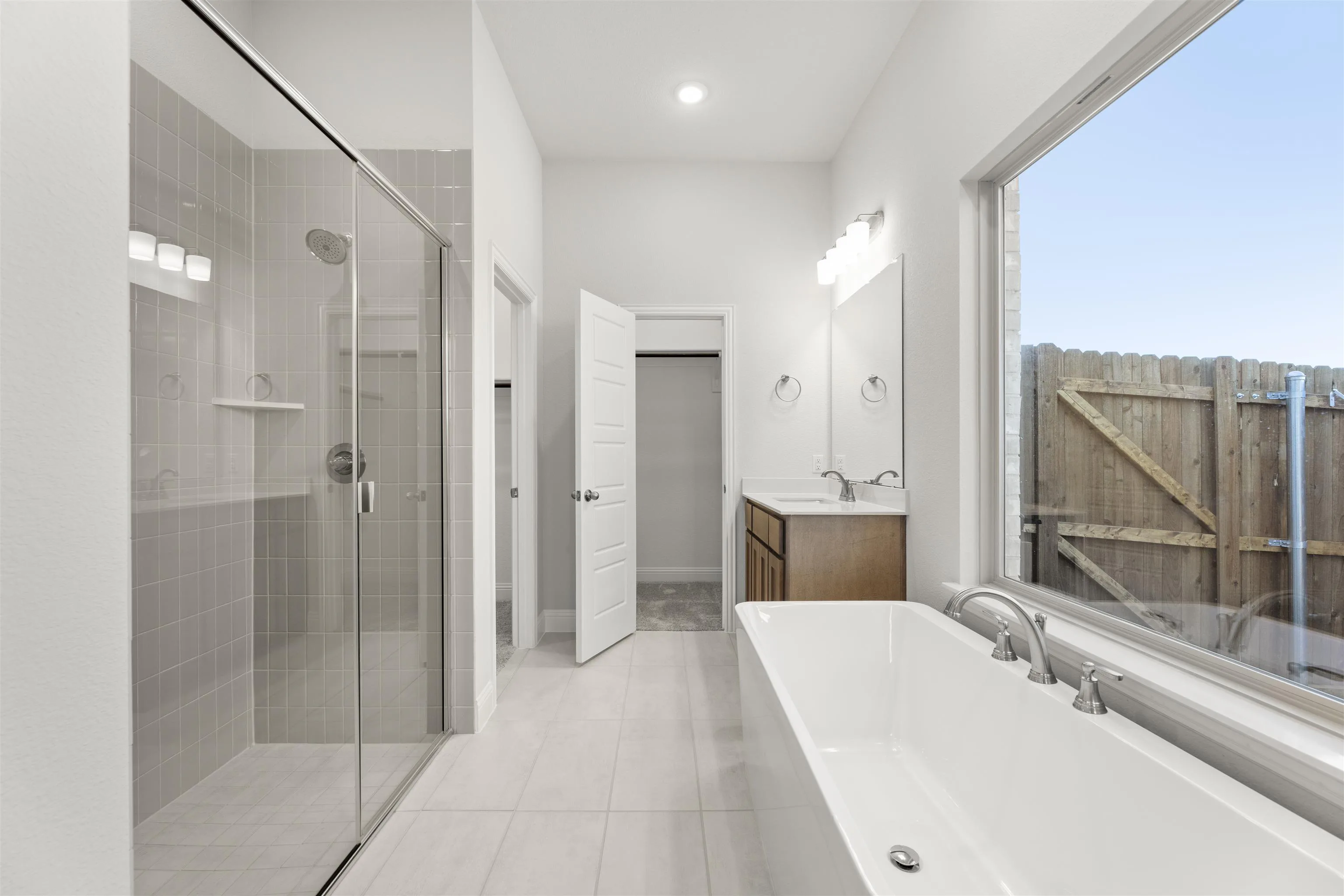 Primary bathroom with walk-in shower and freestanding tub in a new traditional style home by Kindred Homes