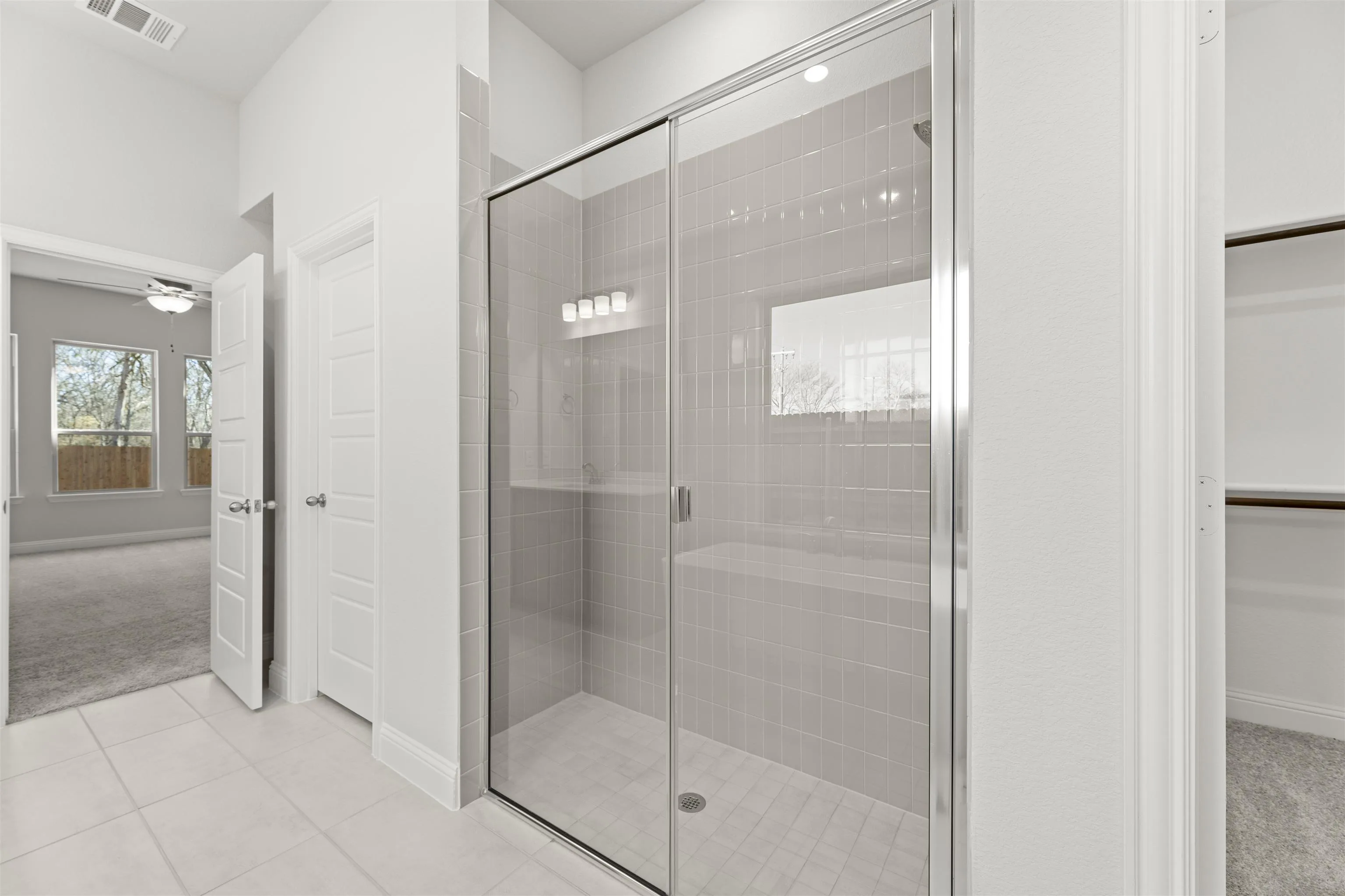 Primary bathroom with walk-in shower in a new traditional style home by Kindred Homes