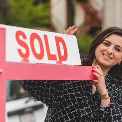 Image of Realtor Holding a sold sign in front of a house