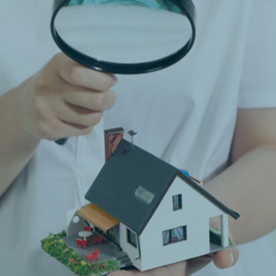 Image of a completed home with a magnifying glass held over to illustrate the final inspection