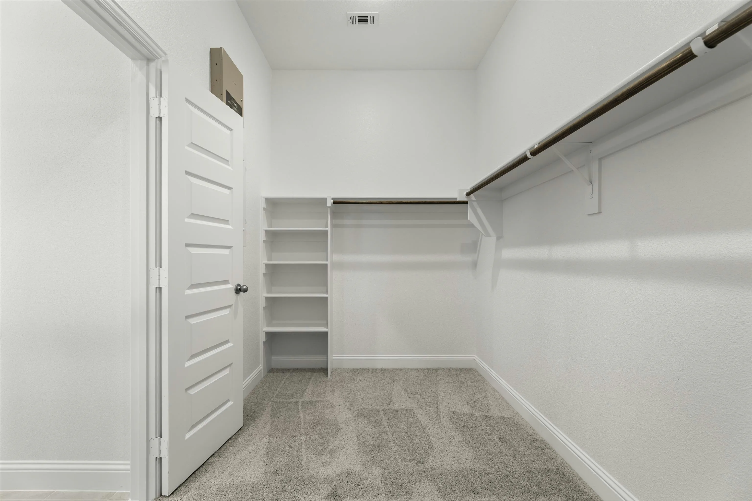Walk-in closet with built-in shelves in modern farmhouse transitional style home by Kindred Homes