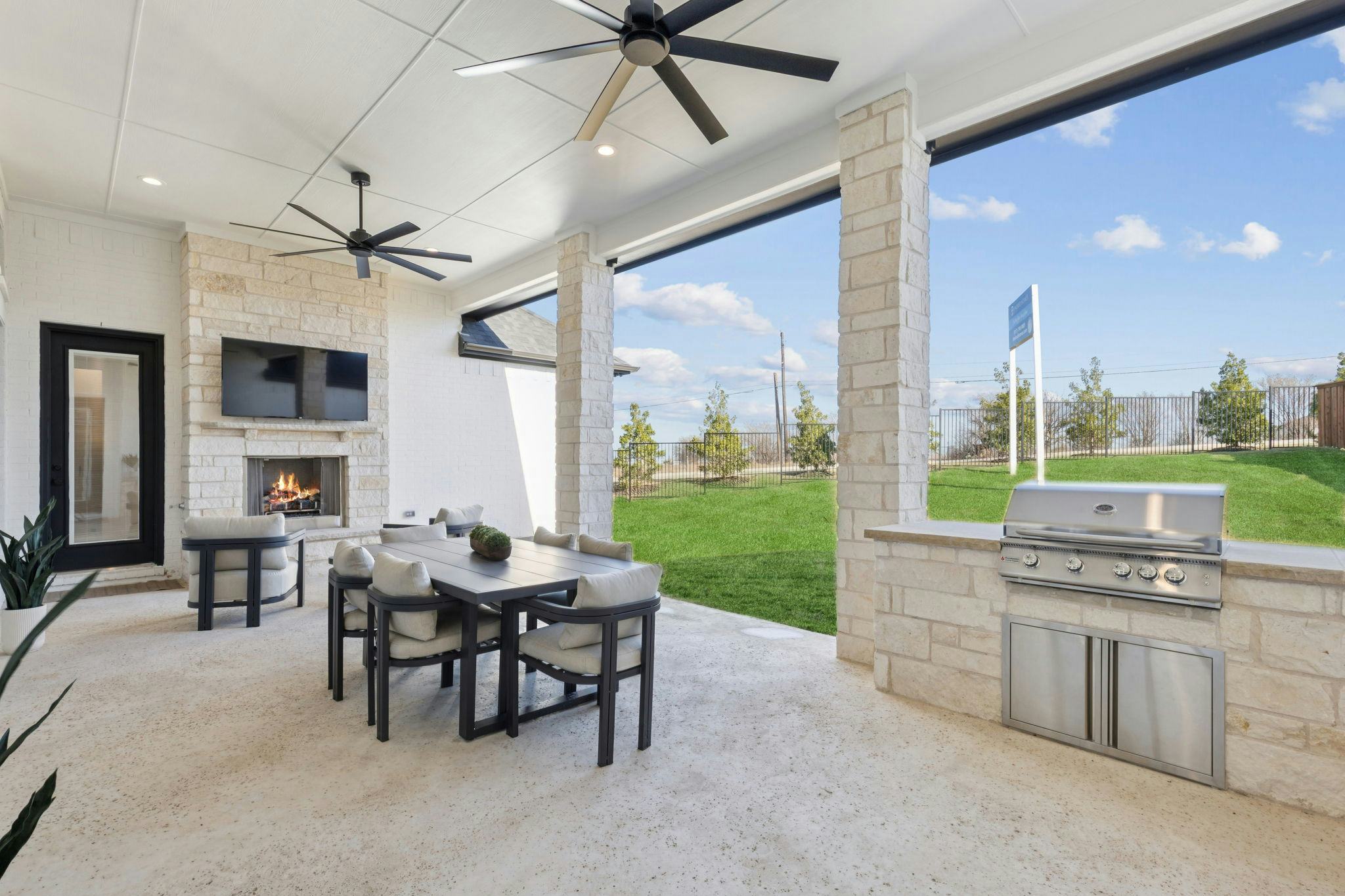Covered outdoor living with outdoor fireplace and grilling station of the custom model home at The Vines by Kindred Homes