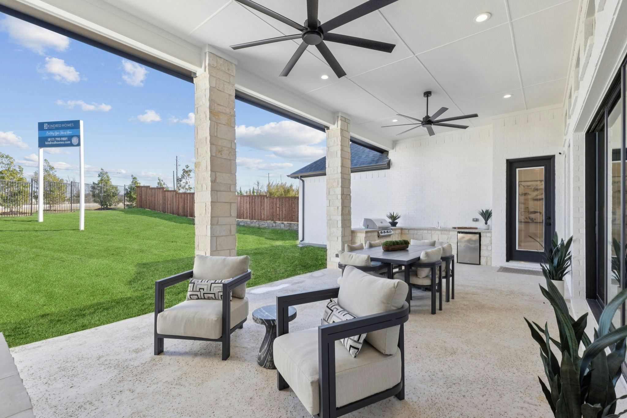 Covered outdoor living and back yard of the custom model home at The Vines by Kindred Homes