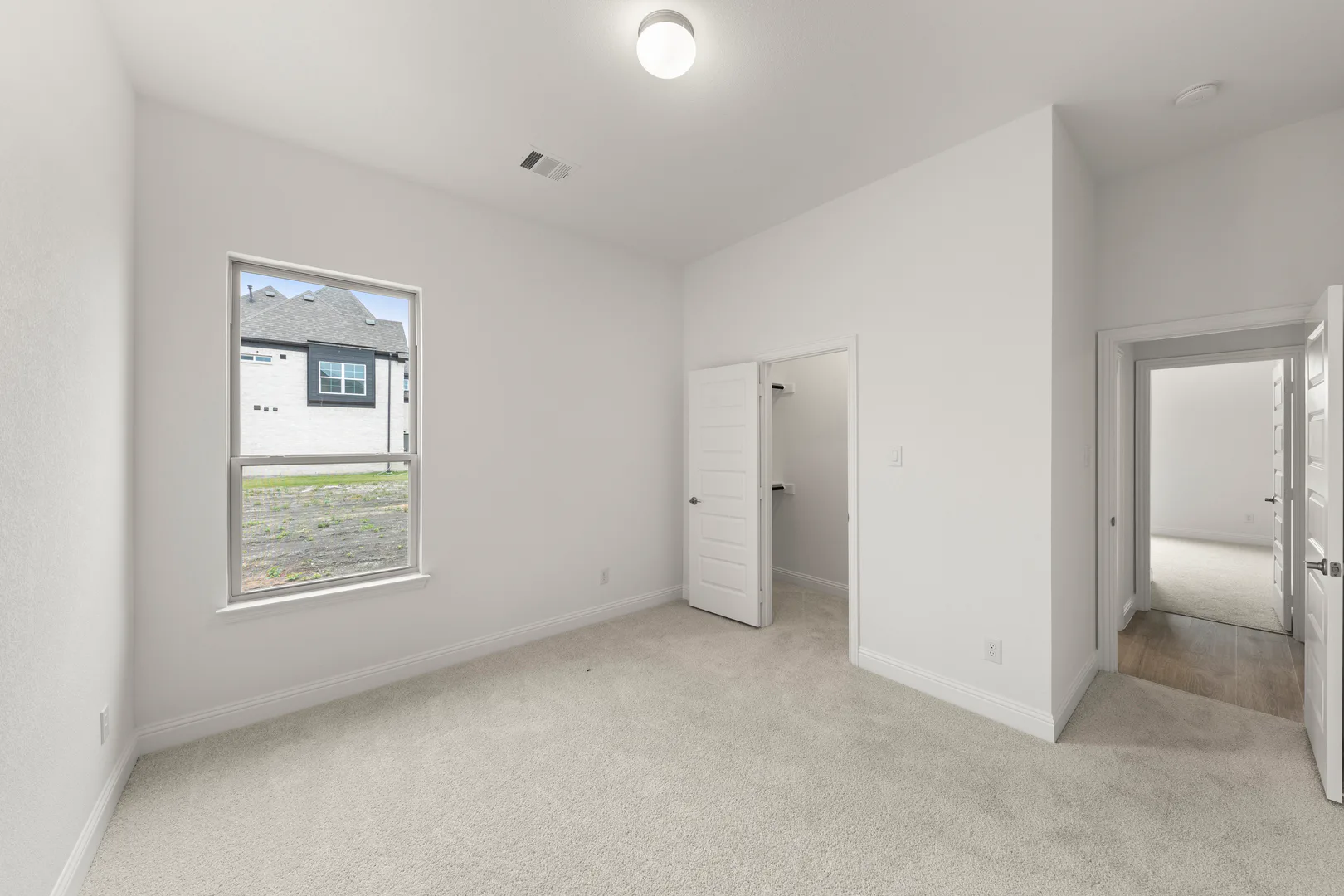 Secondary bedroom with walk-in closet in a modern tudor style home by Kindred Homes