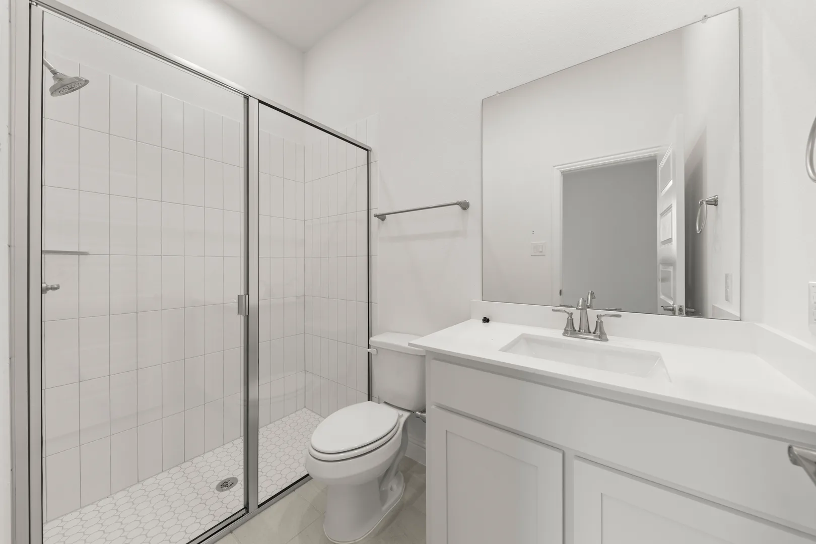 Secondary bathroom with walk-in shower and vanity in a modern tudor style home by Kindred Homes