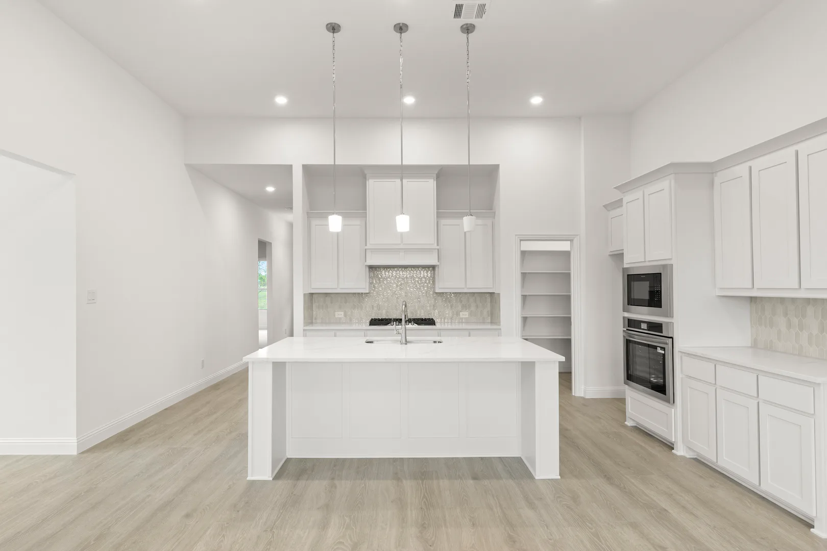 Open concept kitchen with hood vent in a modern tudor style home by Kindred Homes