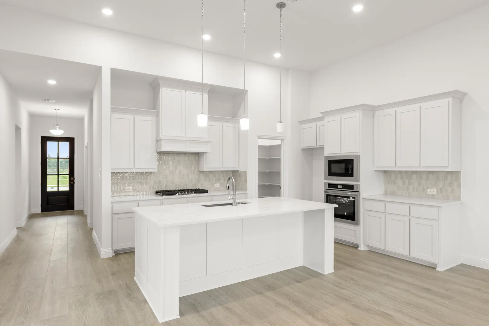 Side view of open concept kitchen with walk-in pantry in a modern tudor style home by Kindred Homes