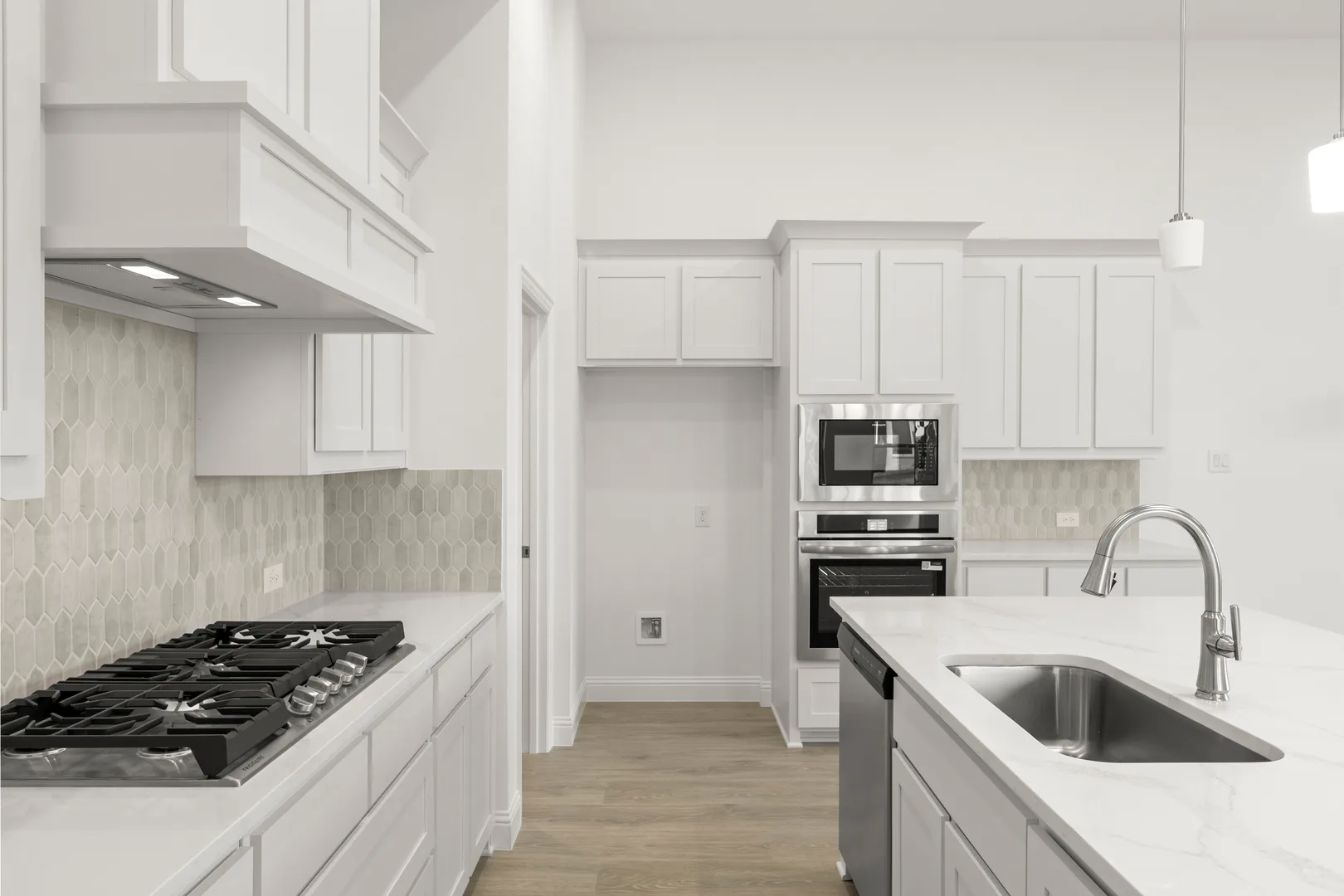 Open concept kitchen with stainless steel appliances in a modern tudor style home by Kindred Homes