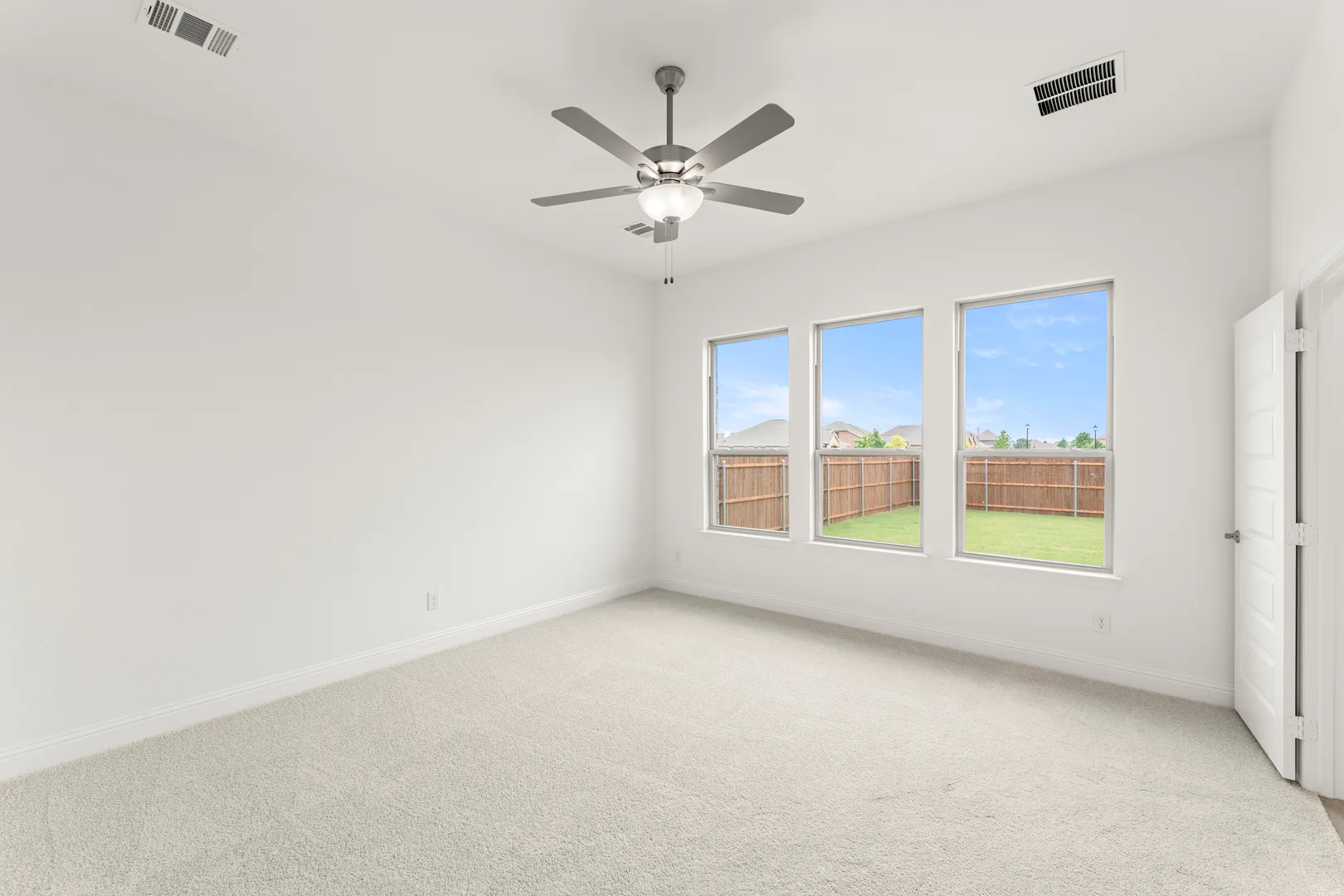 Primary bedroom with three windows in a modern tudor style home by Kindred Homes