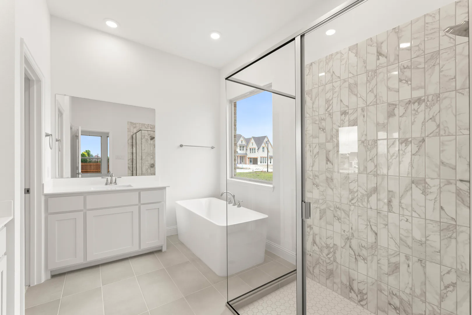 Primary bathroom with walk-in shower and freestanding tub in a modern tudor style home by Kindred Homes