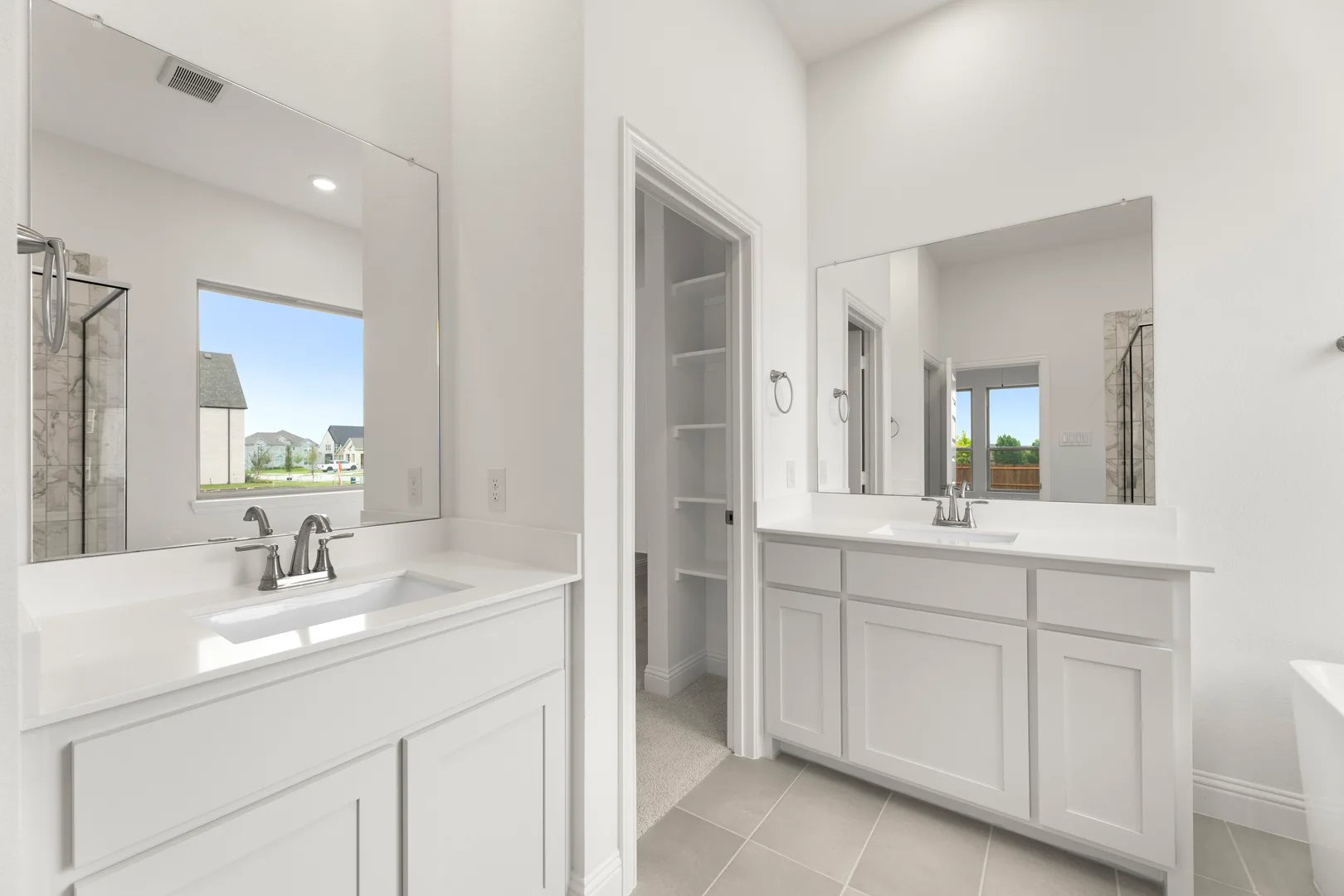 Primary bathroom with dual vanities in a modern tudor style home by Kindred Homes