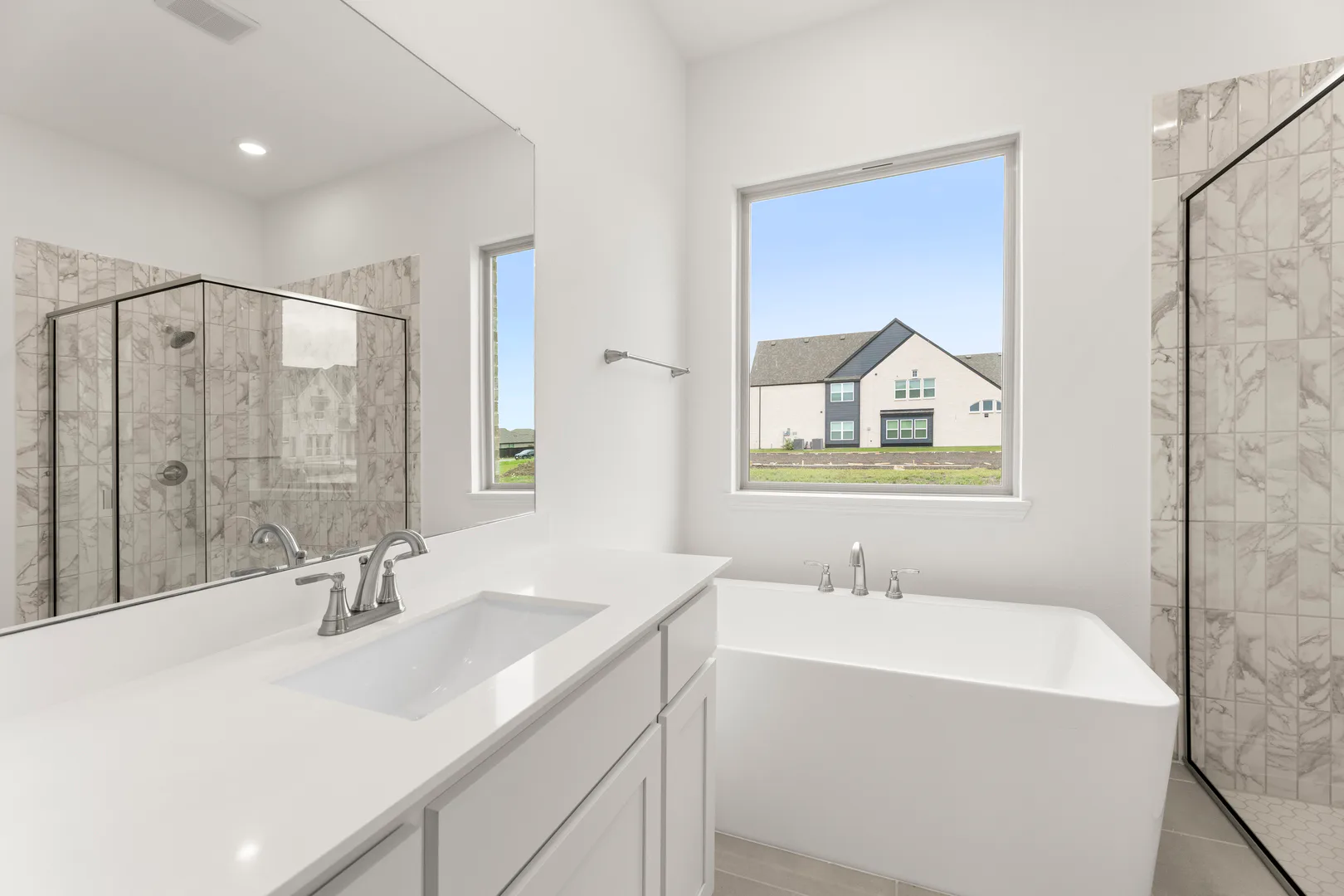 Primary bathroom with freestanding tub in a modern tudor style home by Kindred Homes