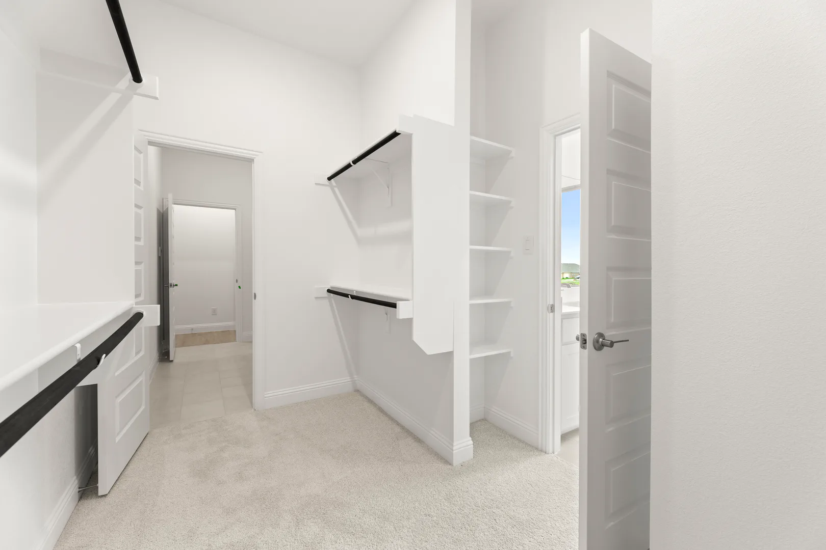 Walk-in closet with built-in shelves in a modern tudor style home by Kindred Homes
