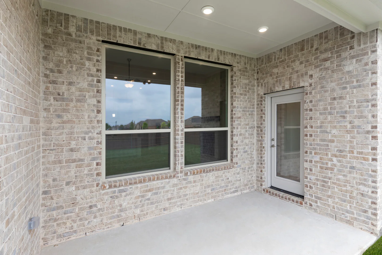 Covered back patio of a modern tudor style home by Kindred Homes