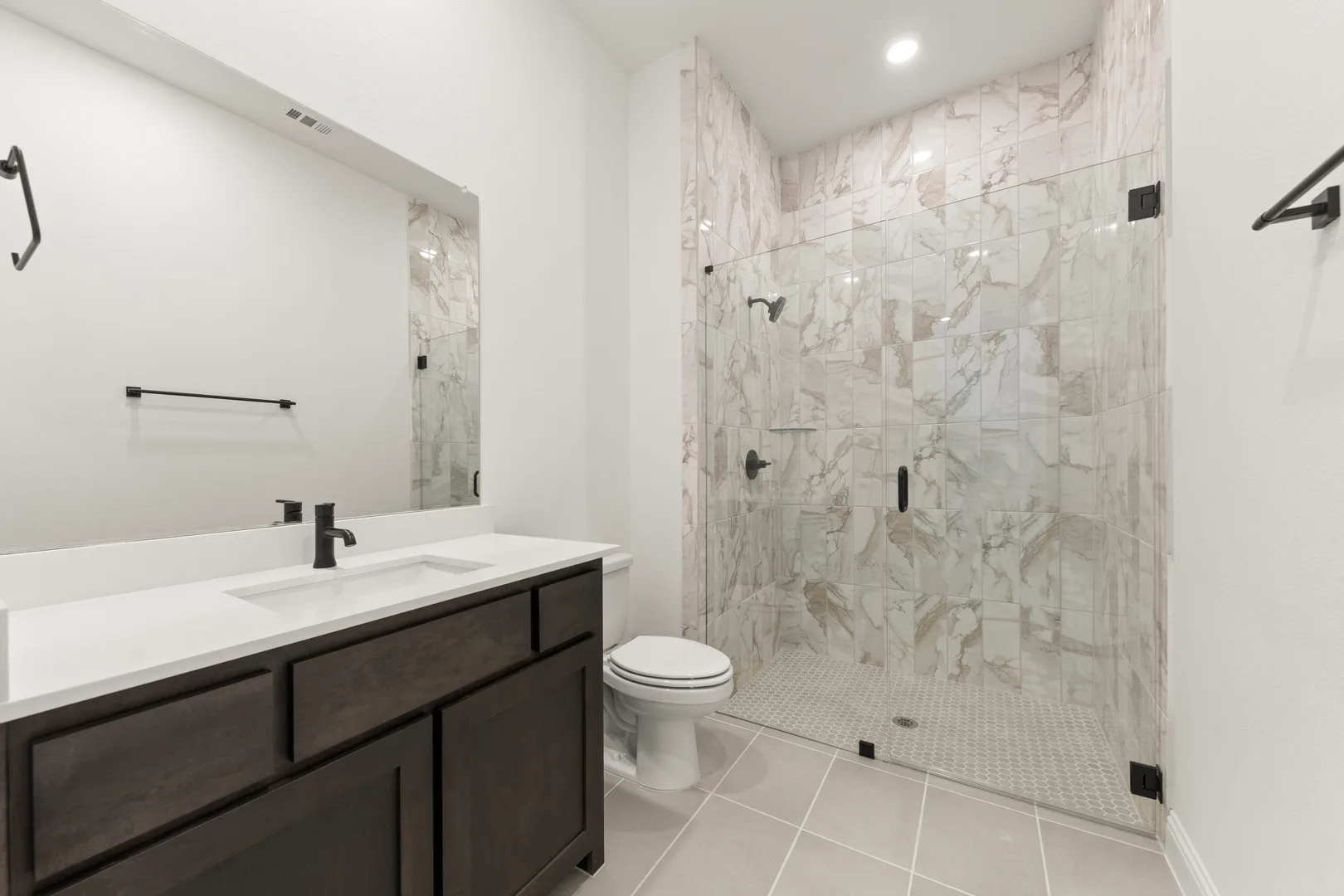 Secondary bathroom with vanity and walk-in shower in a transitional ranch style home by Kindred Homes