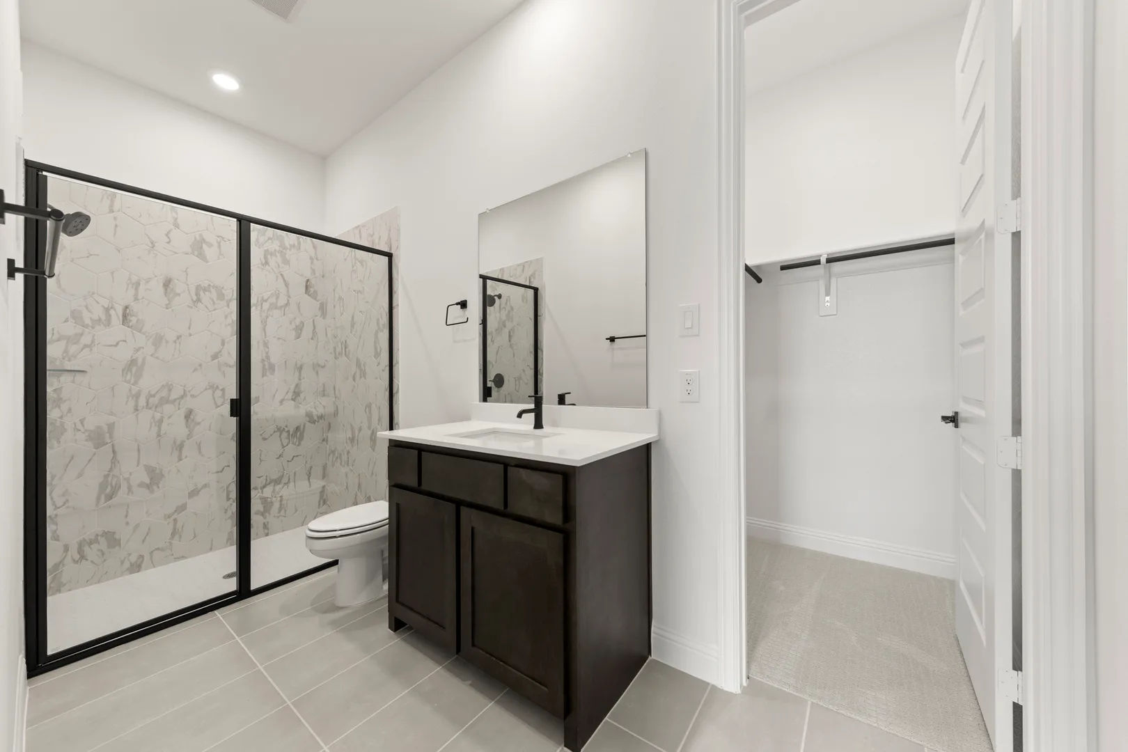 Secondary bathroom with vanity and walk-in shower in a transitional ranch style home by Kindred Homes