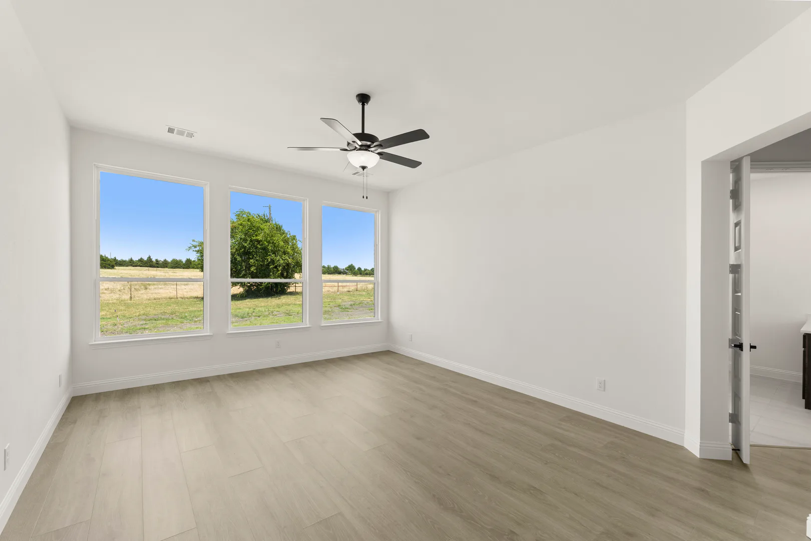 Primary bedroom with natural light in a transitional ranch style home by Kindred Homes