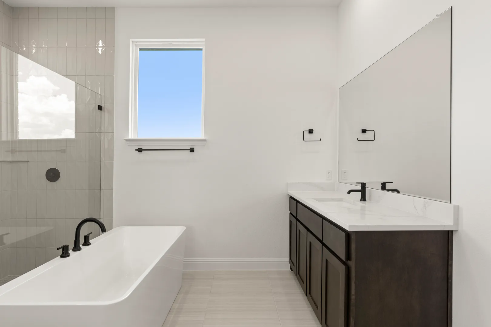 Primary bathroom with separate vanities and freestanding tub in a transitional ranch style home by Kindred Homes