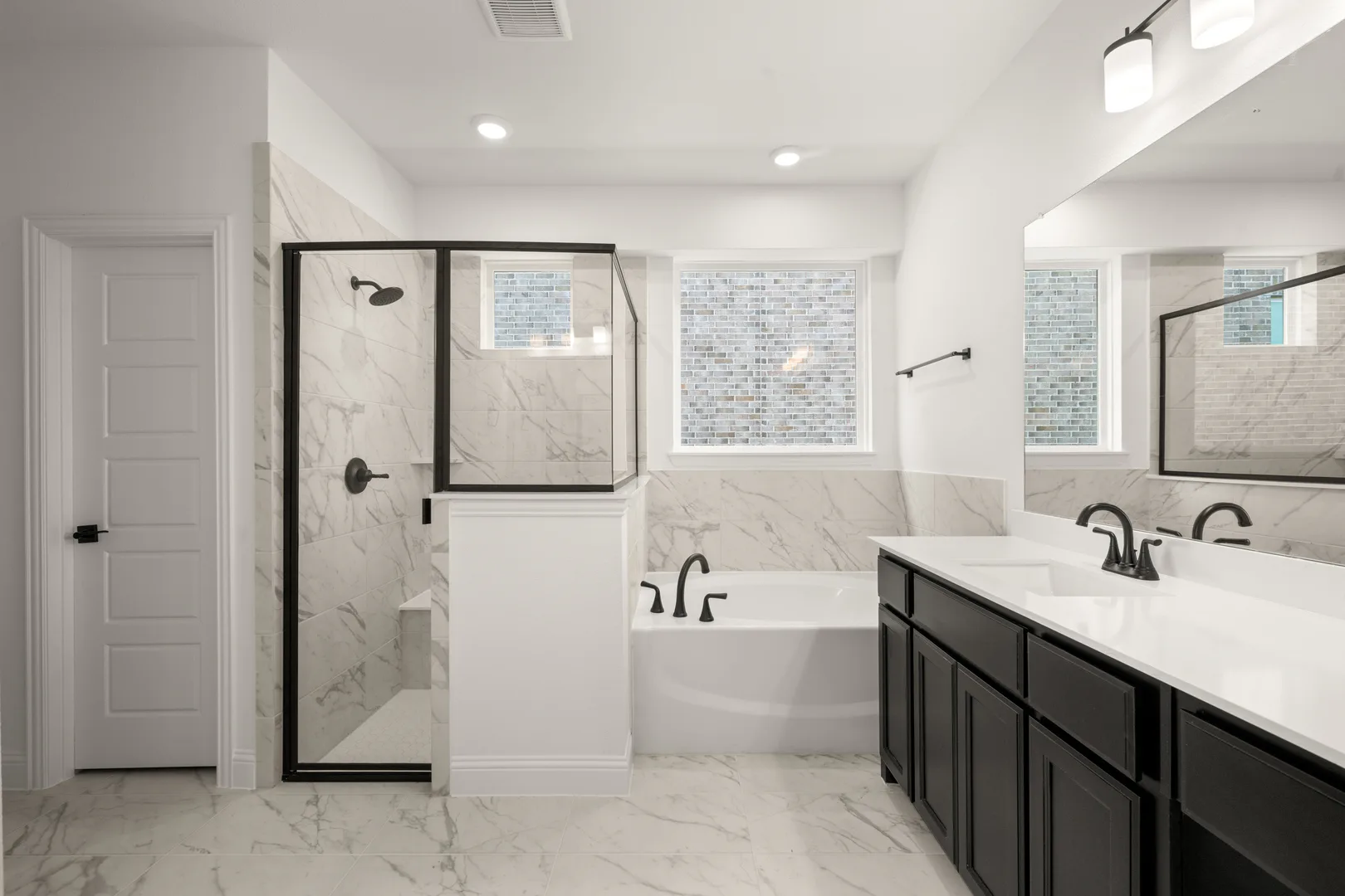Primary bathroom with shower and bathtub in a new traditional style home by Kindred Homes