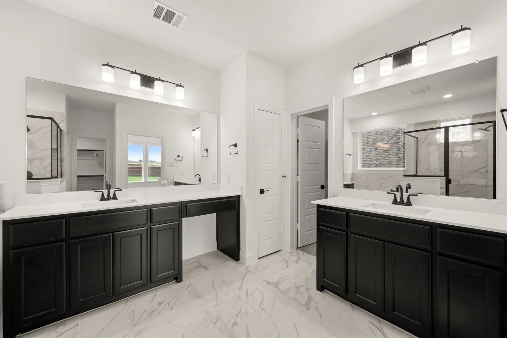 Primary bathroom with dual vanities in a new traditional style home by Kindred Homes