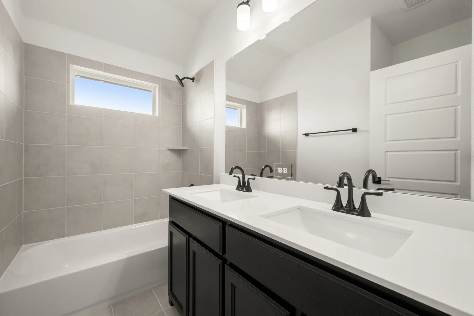 Secondary bathroom with dual vanity in a new traditional style home by Kindred Homes