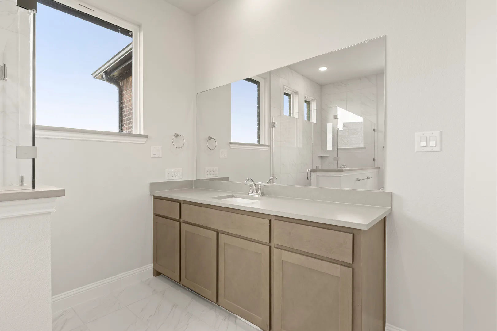 Primary bathroom with dual vanities in a transitional ranch style home by Kindred Homes