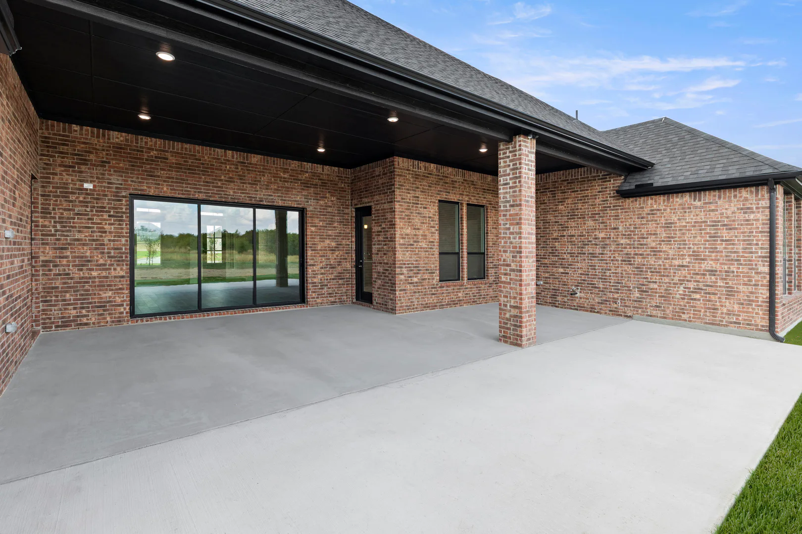 Covered patio with sliding glass doors in a transitional ranch style home by Kindred Homes