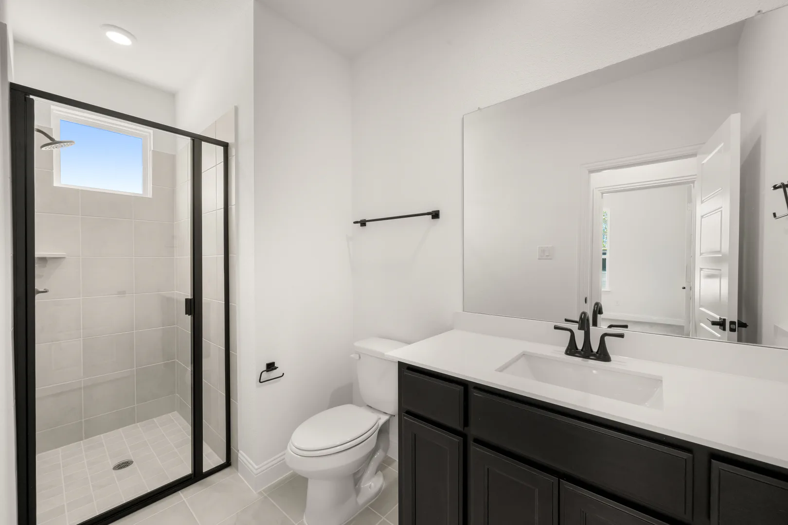 Secondary bathroom with walk-in shower in a new traditional style home by Kindred Homes