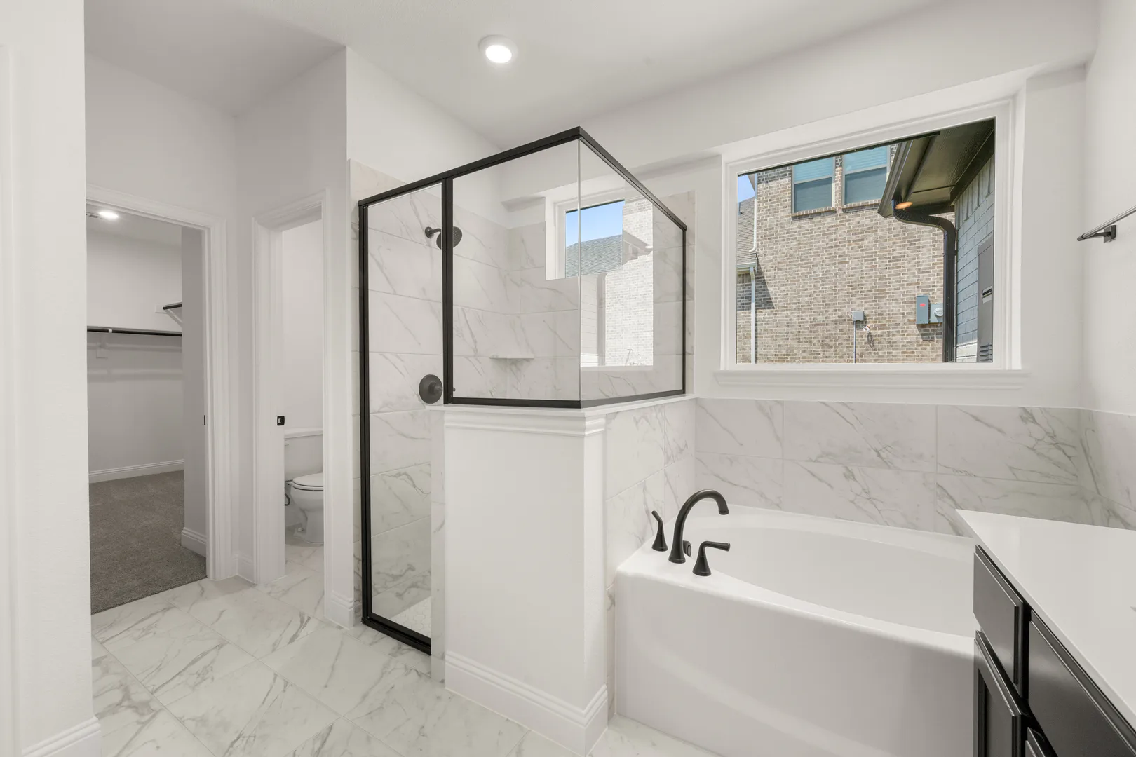 Primary bathroom with a walk-in shower and garden style tub in a new traditional style home by Kindred Homes