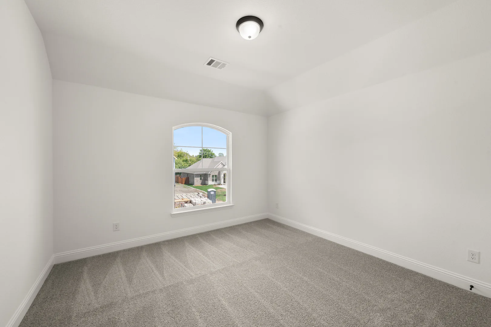 Secondary bedroom with arched window in a new traditional style home by Kindred Homes