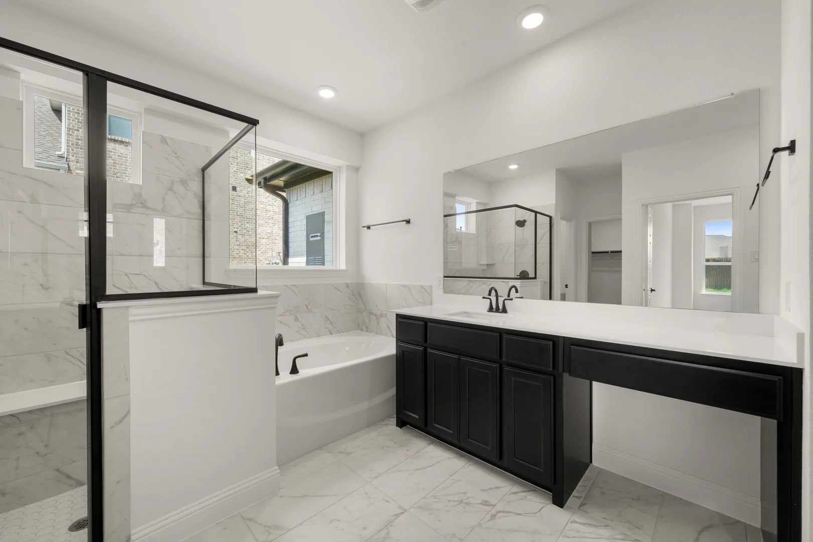 Primary bathroom with garden style tub and walk-in shower in a new traditional style home by Kindred Homes