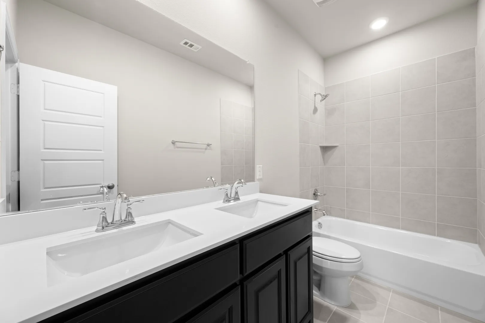 Secondary bathroom with dual vanity and a bath tub shower in a transitional ranch style home by Kindred Homes
