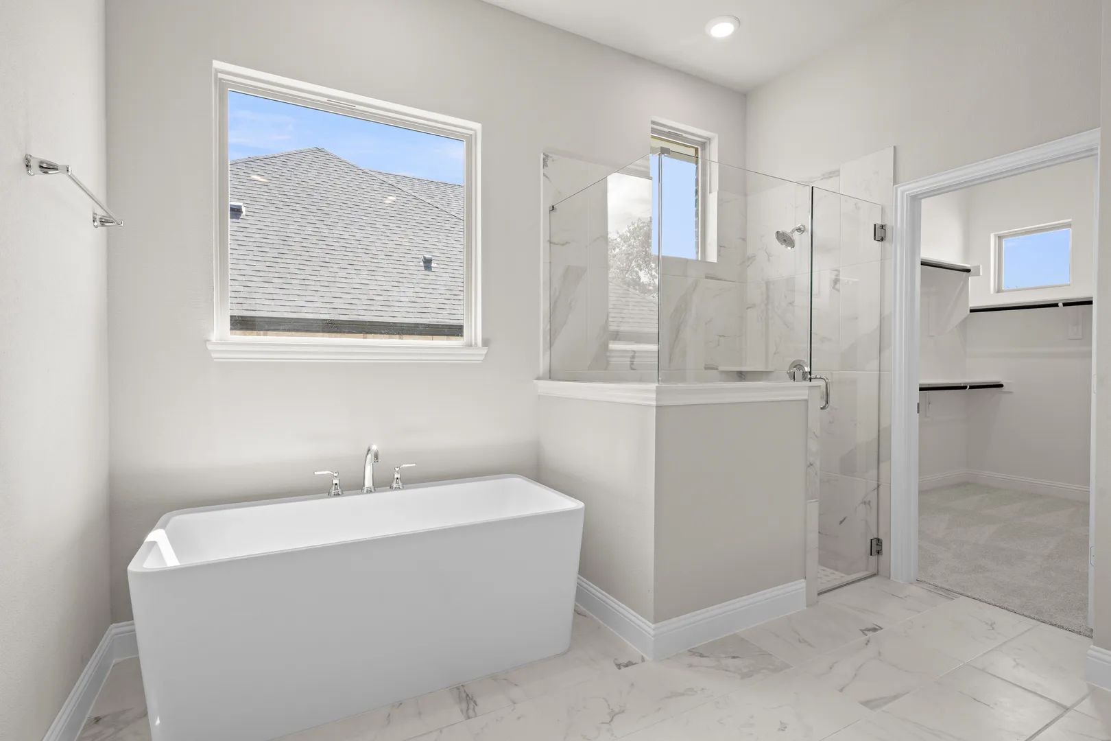 Primary bathroom with freestanding tub and walk-in shower in a transitional ranch style home by Kindred Homes