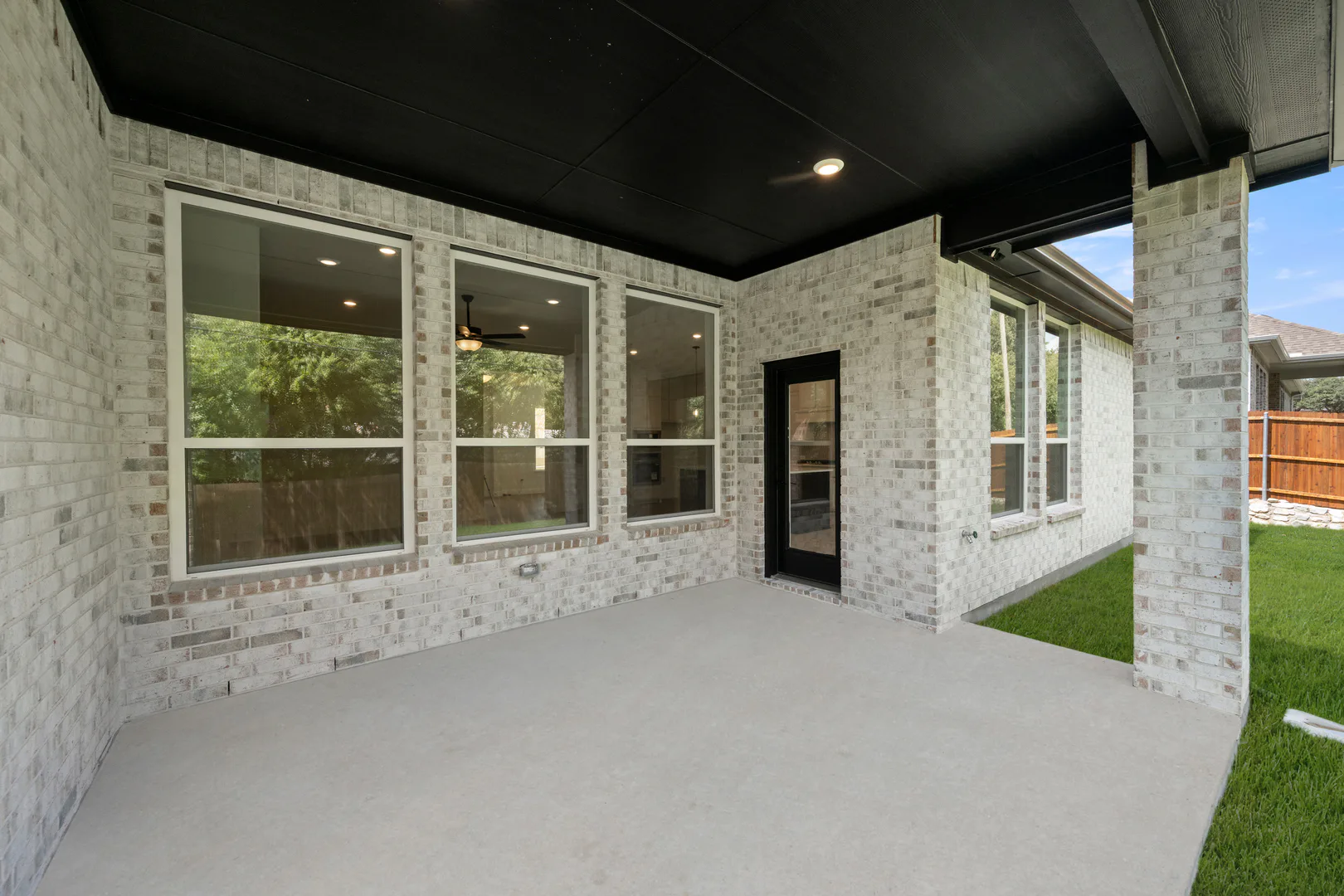 Covered patio in a transitional ranch style home by Kindred Homes