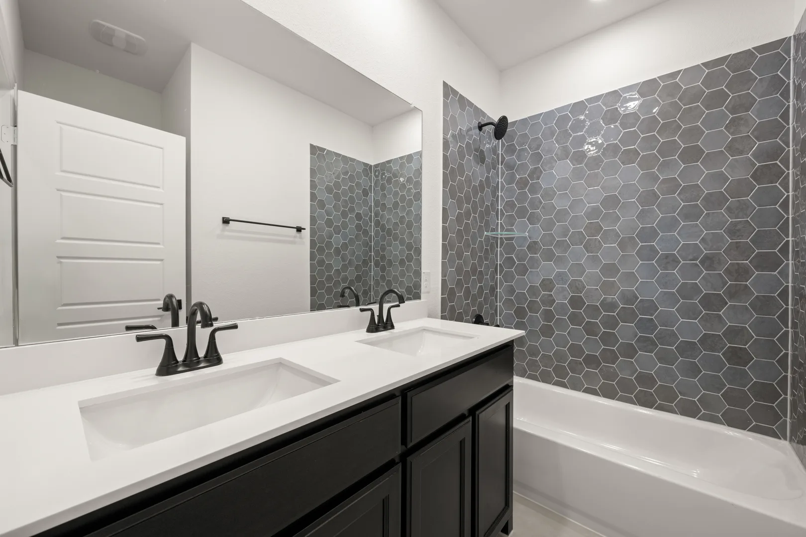 Secondary bathroom with dual vanity and shower/tub in a transitional ranch style home by Kindred Homes