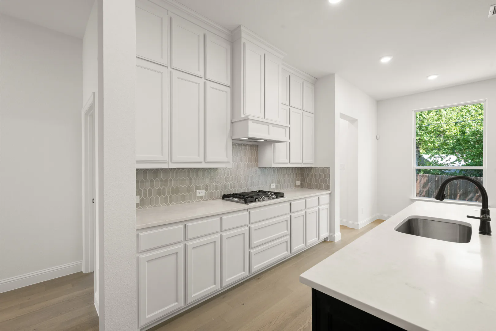 Kitchen with grey tile backsplash in a transitional ranch style home by Kindred Homes