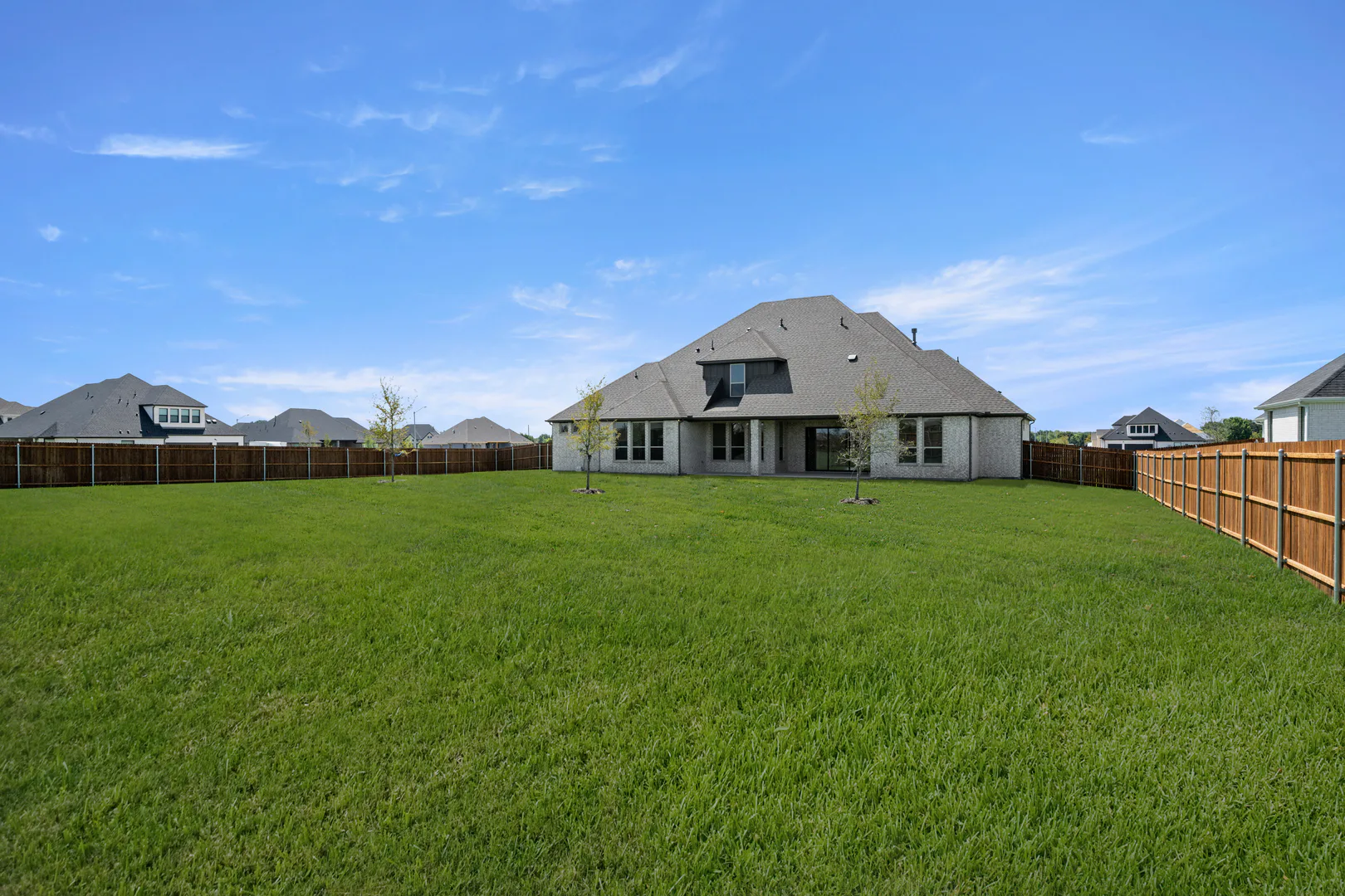 Spacious backyard of a modern Texas ranch style home by Kindred Homes