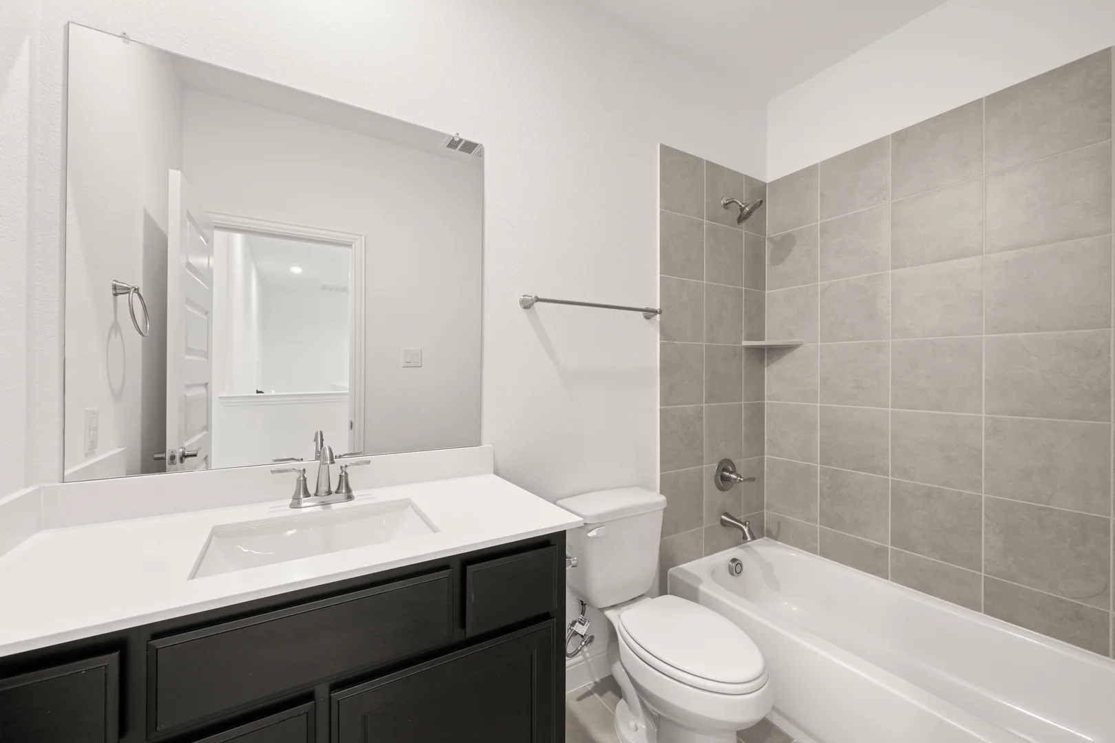 Secondary bathroom with tub/shower in a modern Texas ranch style home by Kindred Homes