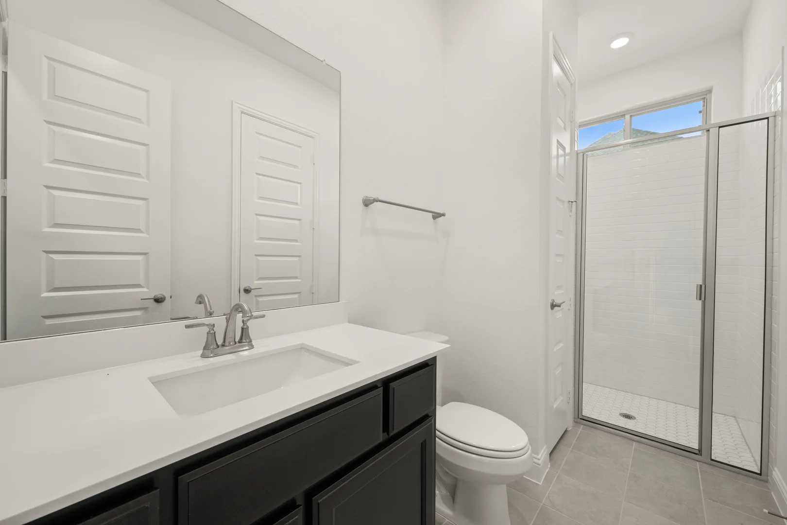 Secondary bathroom with walk-in shower in a modern Texas ranch style home by Kindred Homes