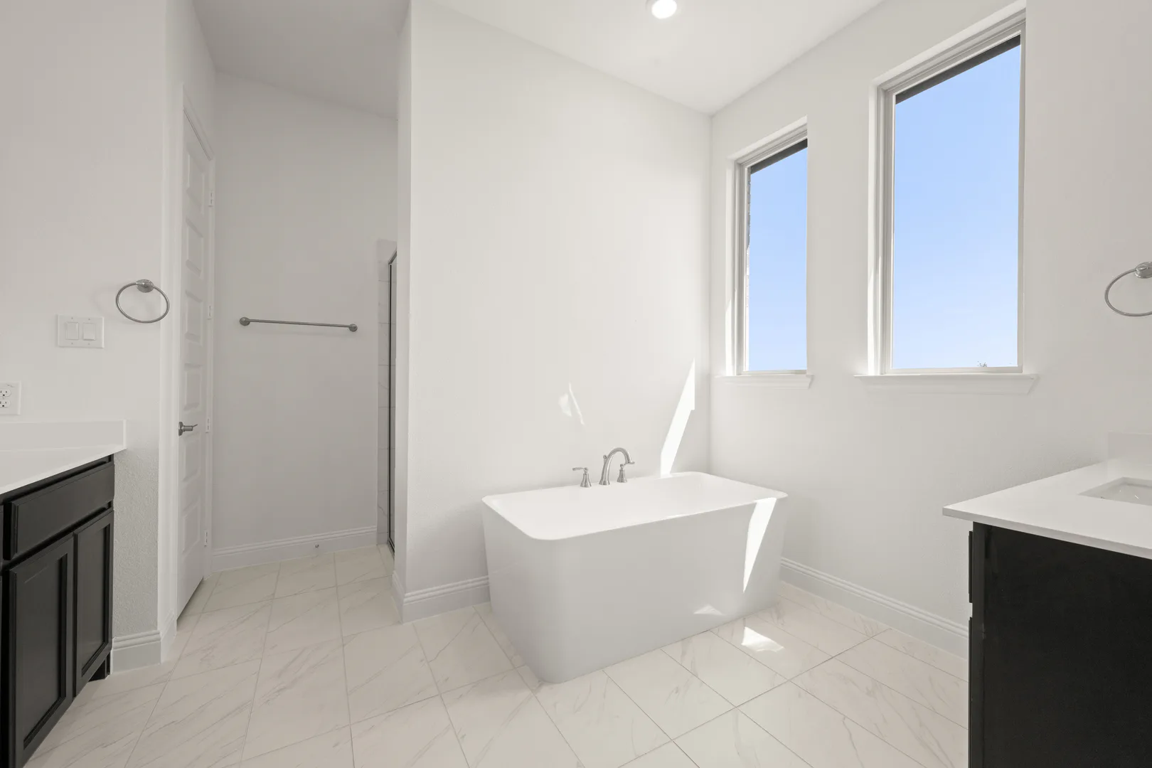 Secondary bathroom with a freestanding tub in a modern Texas ranch style home by Kindred Homes