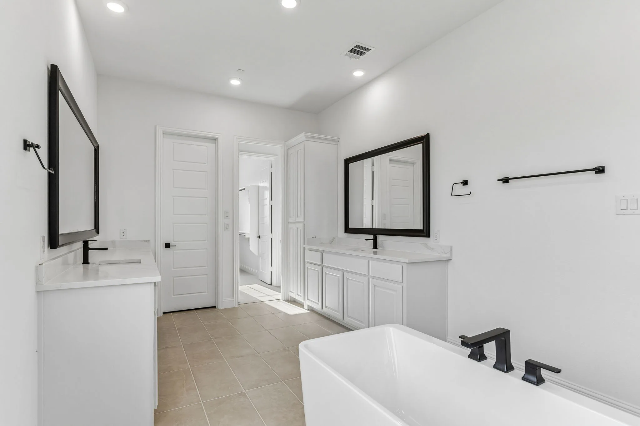 Primary bathroom with dual vanities in a transitional hill country style home by Kindred Homes.