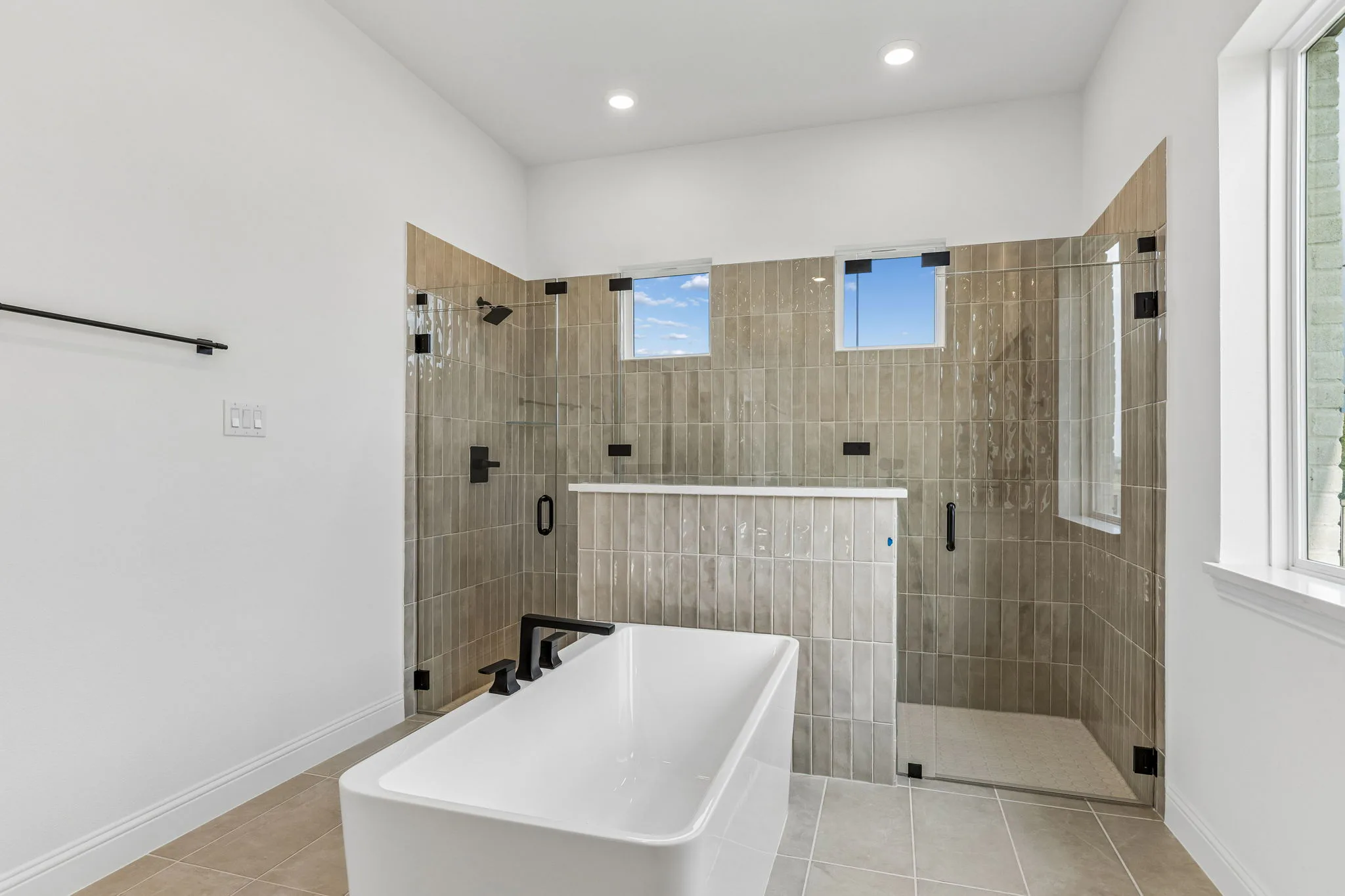 Primary bathroom with freestanding tub and walk-in shower in a transitional hill country style home by Kindred Homes.
