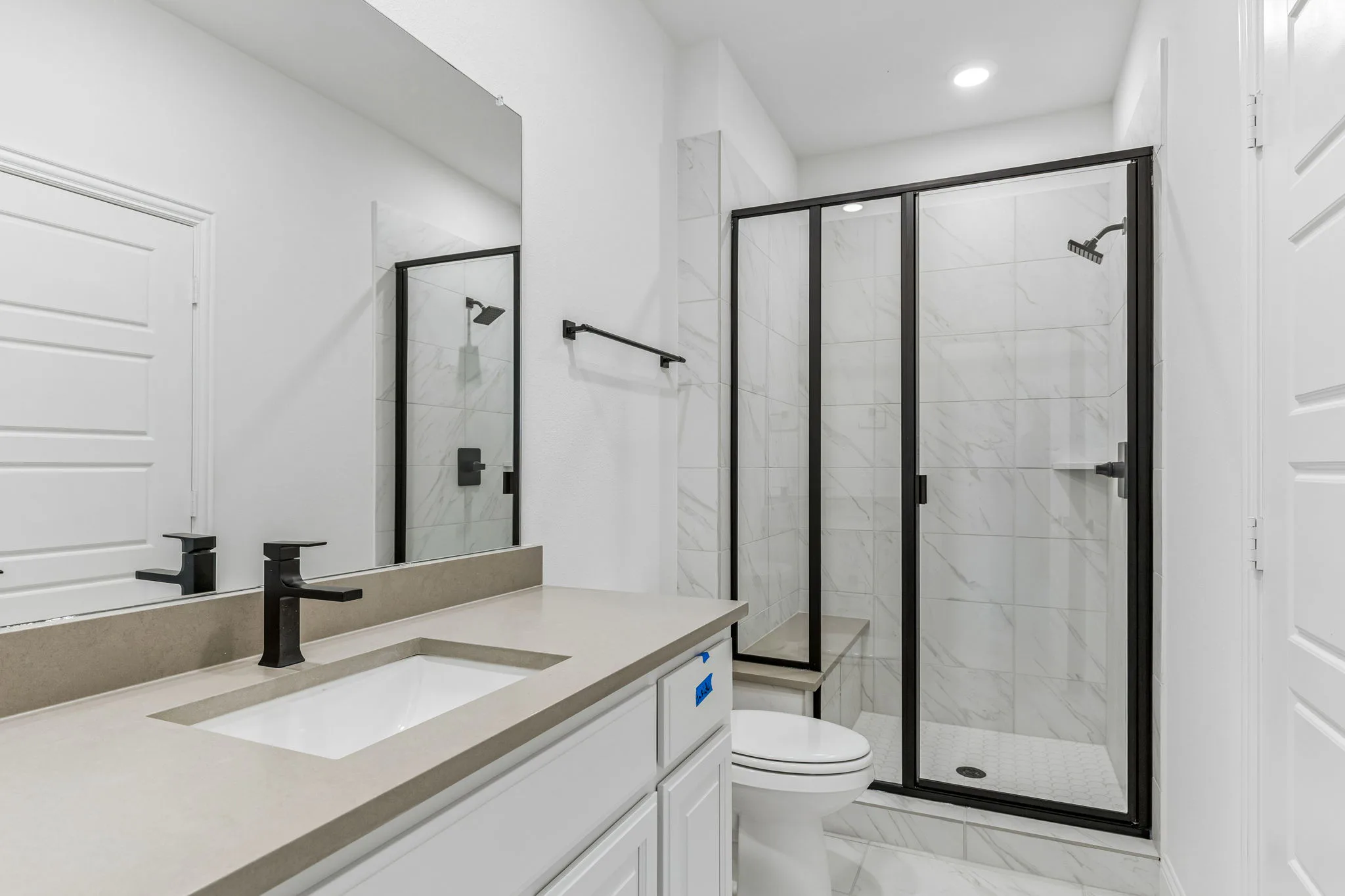 Secondary bathroom with walk-in shower in a transitional hill country style home by Kindred Homes.