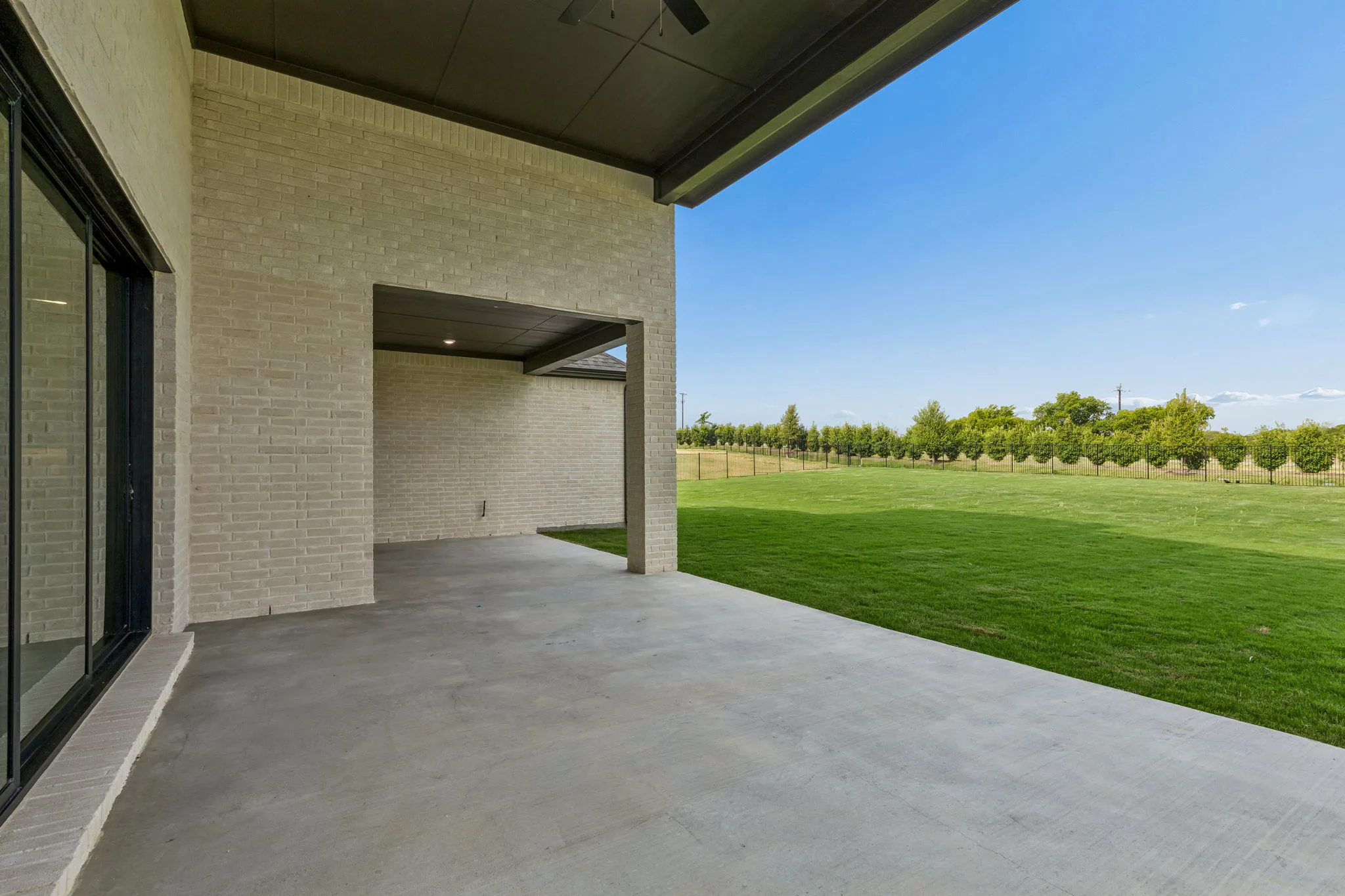 Covered back patio in a transitional hill country style home by Kindred Homes.