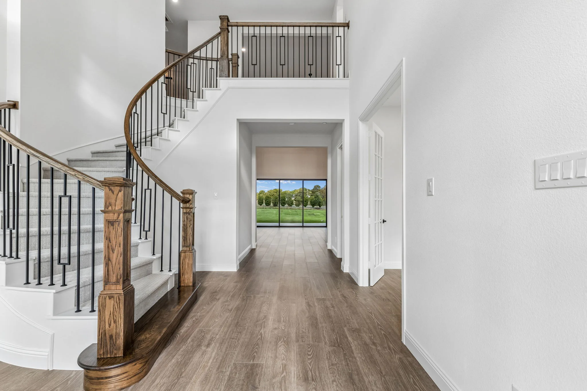 Entryway with curved staircase in a transitional hill country style home by Kindred Homes.