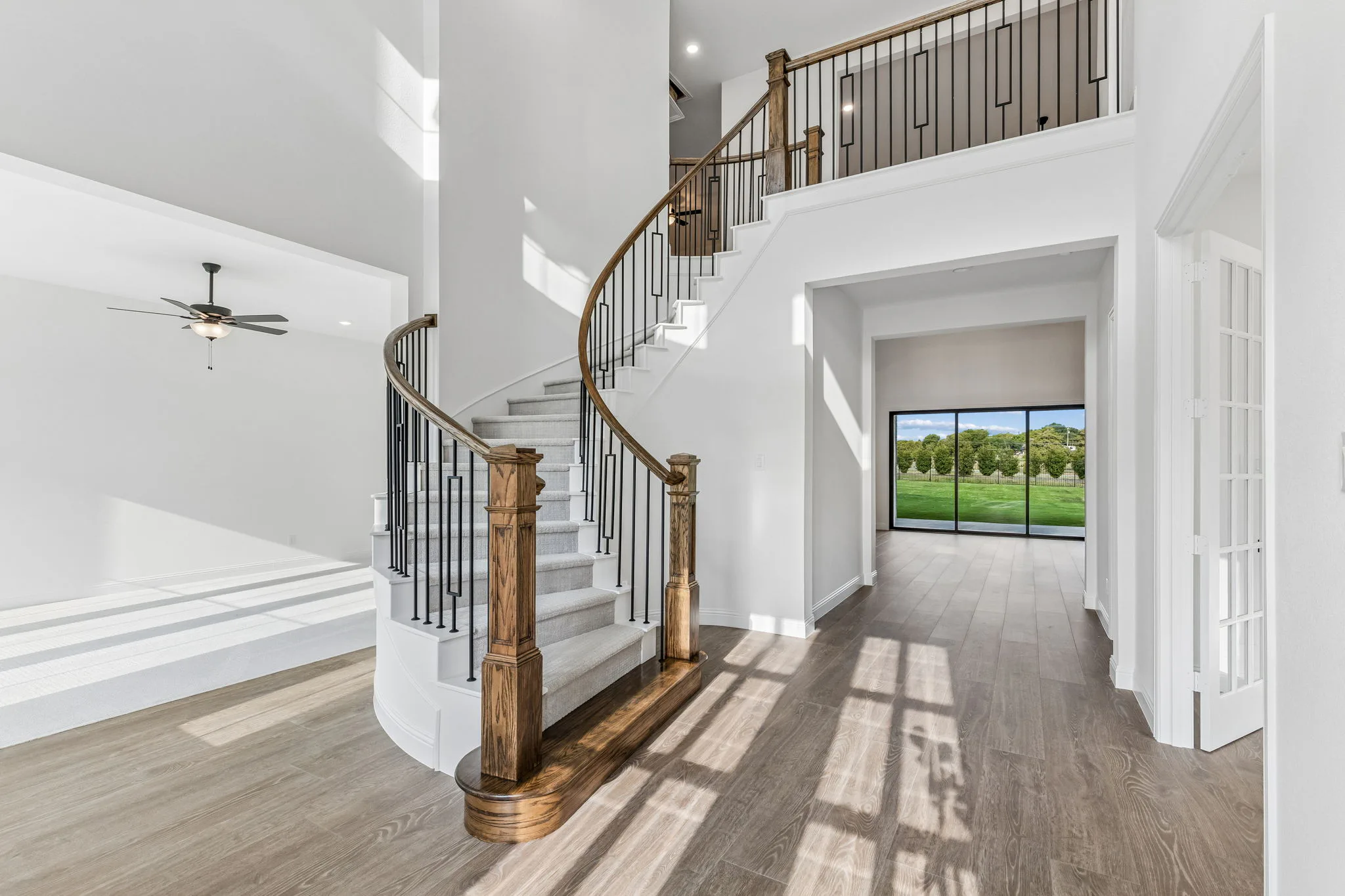 Entryway with curved staircase in a transitional hill country style home by Kindred Homes.