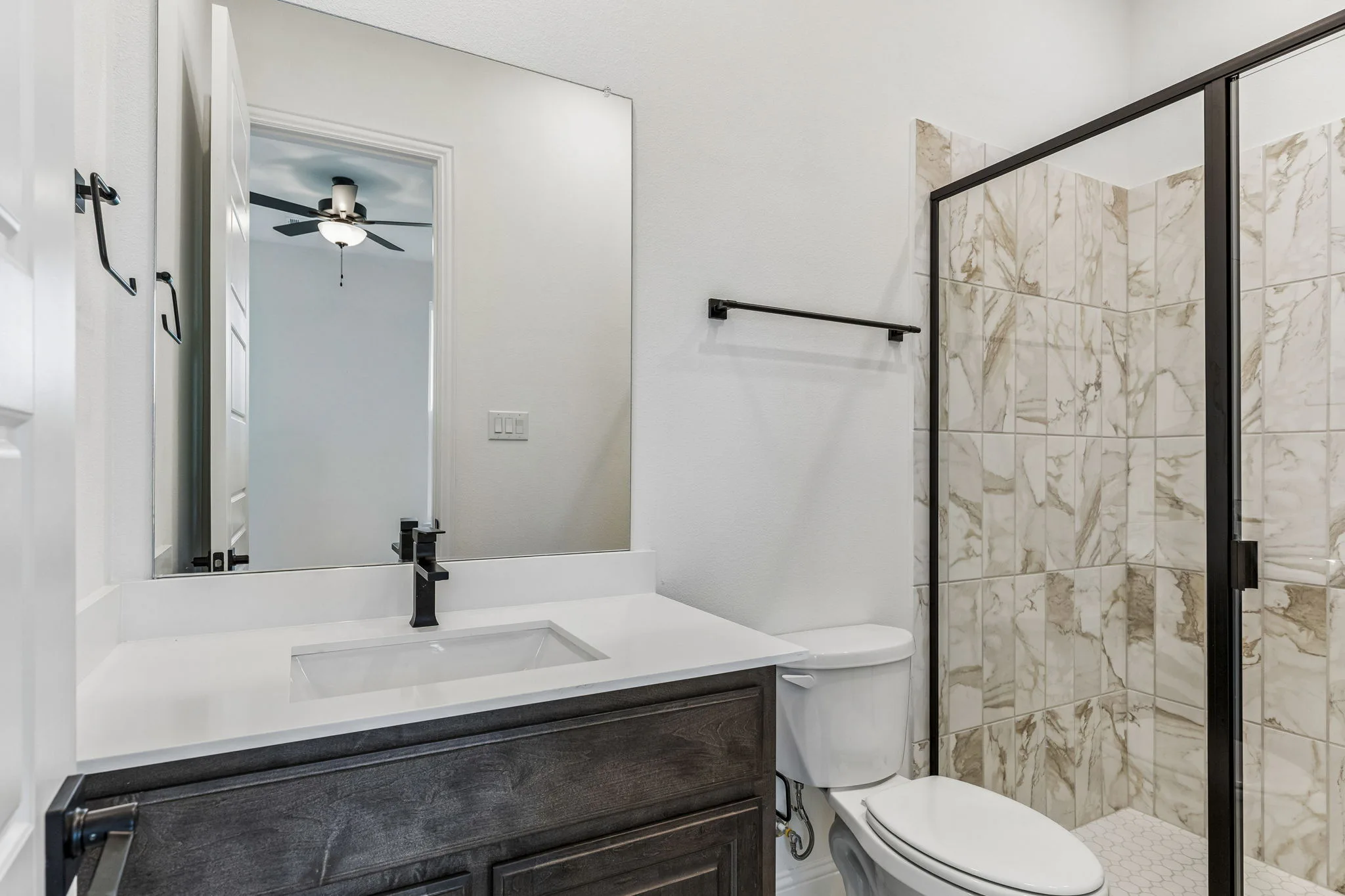 Secondary bathroom with walk-in shower in a transitional hill country style home by Kindred Homes.
