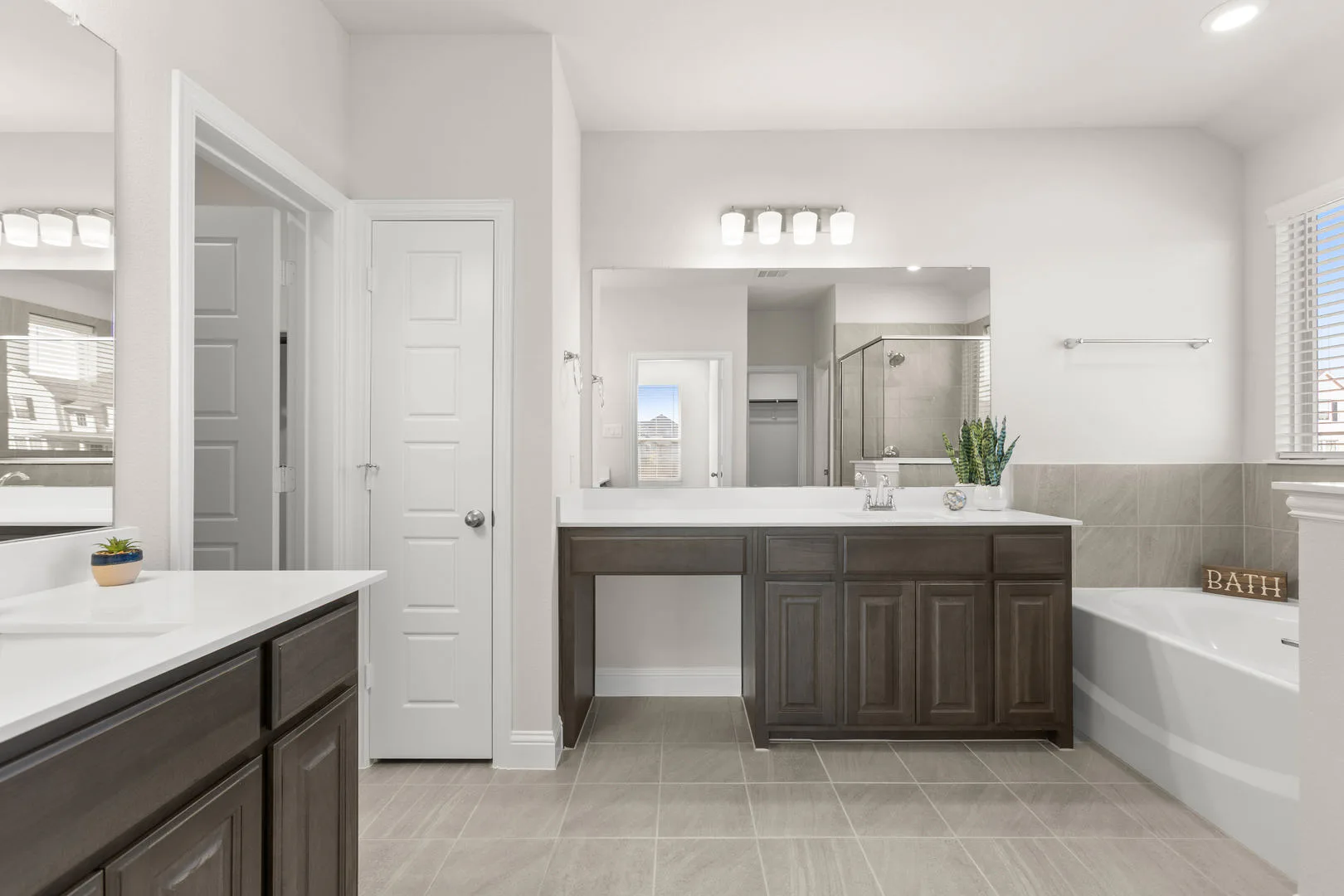 Primary bathroom with dual vanities in a new traditional style home by Kindred Homes