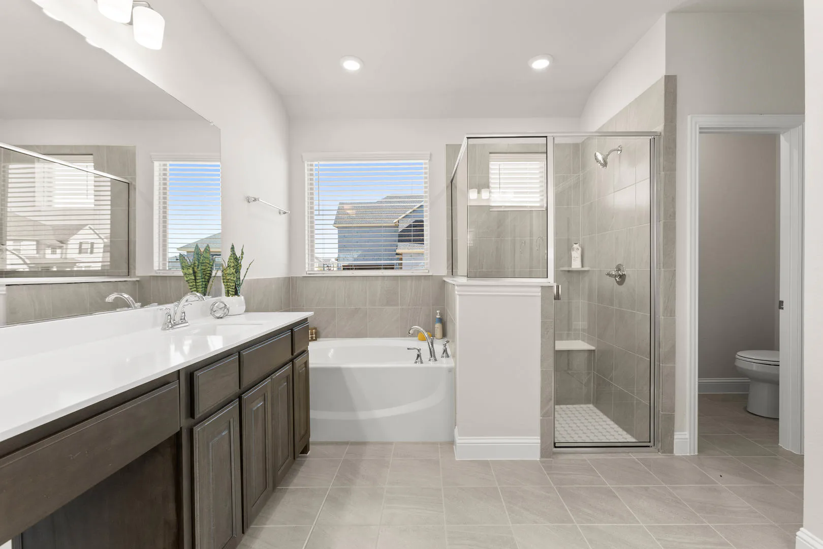 Primary bathroom with a seperate bathtub and walk-in shower in a new traditional style home by Kindred Homes